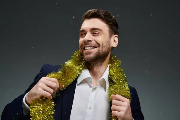 This charming young man joyfully showcases golden garlands while smiling widely. — Stock Photo