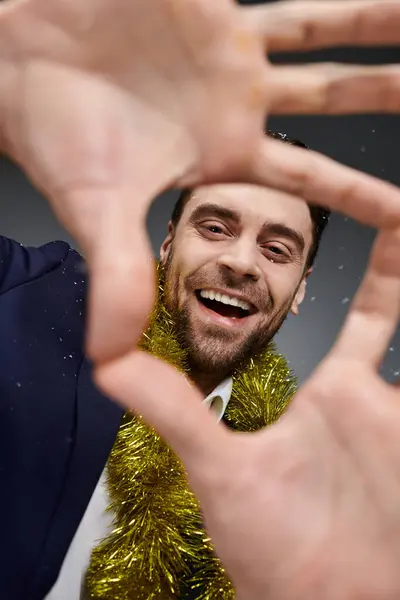 A young man with a big smile frames his face with hands decorated in festive attire. — Stock Photo