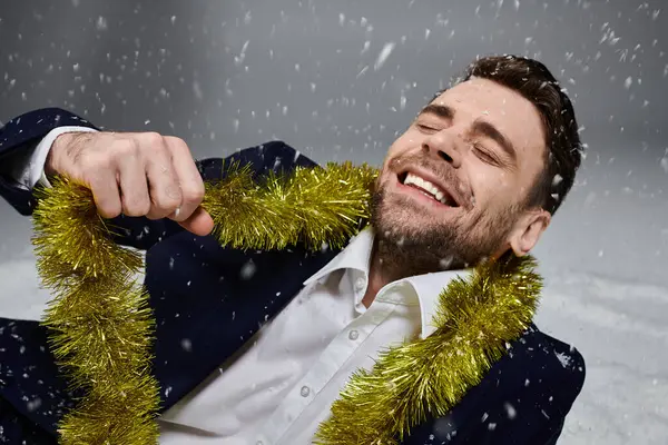 This young man revels in a cheerful moment, joyfully playing with festive garland. — Stock Photo