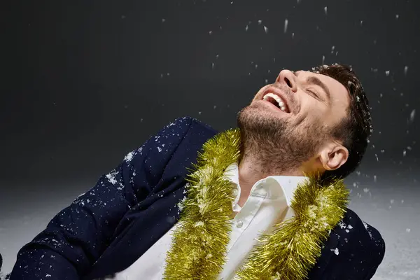Ein gutaussehender junger Mann genießt einen Moment des Lachens, geschmückt mit festlichem Schmuck und Schneeflocken. — Stockfoto