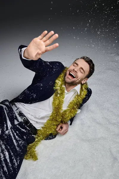 A joyful young man dressed in a suit surrounded by snow, enjoying a festive moment. — Stock Photo