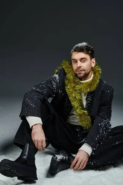 A handsome young man poses in a stylish outfit, adorned with winter decorations and snow. — Stock Photo