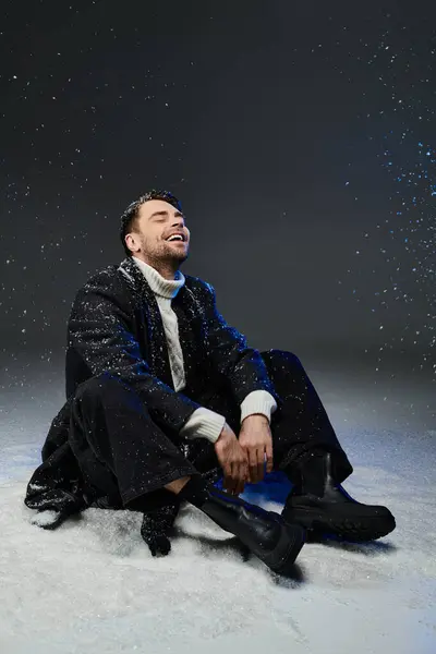 A young man sits happily in a soft snow, embracing the magic of winter indoors. — Stock Photo