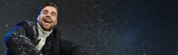 Un giovane allegro immerso nel divertimento invernale, ridendo gioiosamente mentre i fiocchi di neve gli danzano intorno.. — Stock Photo