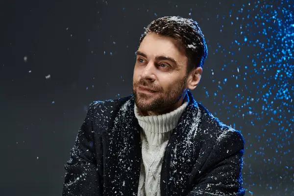 A young gentleman sits gracefully, surrounded by soft falling snowflakes, exuding warmth and charm. — Stock Photo