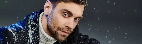 A stylish man stands in snowfall, exuding charisma with a charming expression on a winter day. — Stock Photo