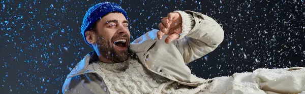 A young man laughs joyfully while surrounded by gentle snowflakes, radiating warmth and happiness. — Stock Photo