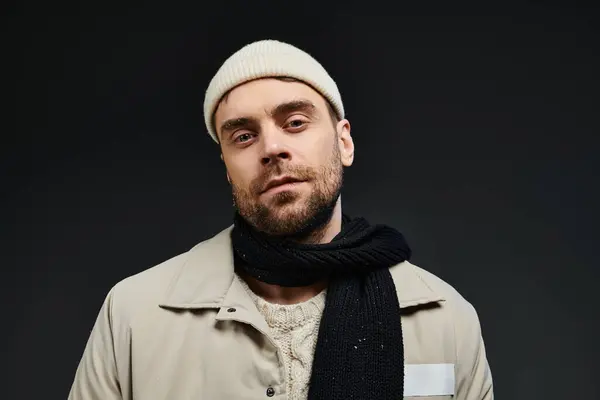A confident young man showcases his trendy winter look with a cozy scarf and stylish beanie. — Stock Photo