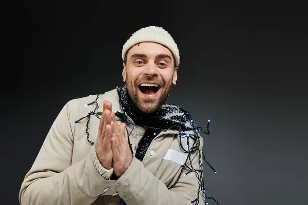 A joyful man dressed warmly claps his hands, embracing the festive winter spirit. — Stockfoto