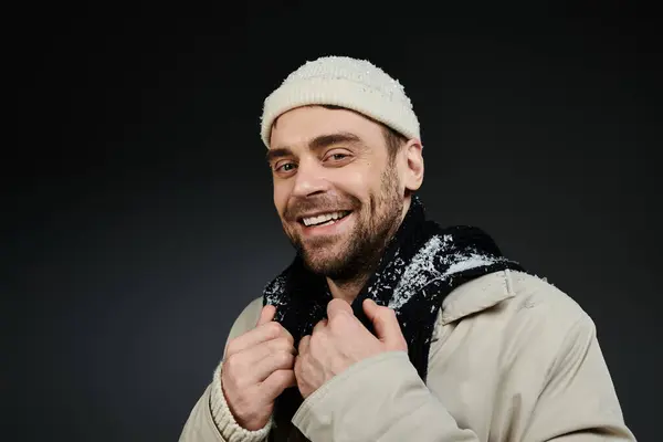 Ein stilvoller junger Mann strahlt Positivität aus, während er seinen Schal mit einem strahlenden Lächeln justiert. — Stockfoto