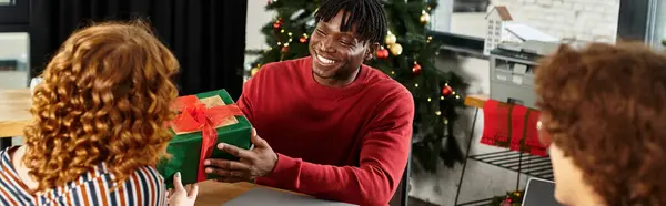 Un groupe de jeunes collègues partage le bonheur tout en se faisant des cadeaux lors d'une célébration de Noël. — Photo de stock