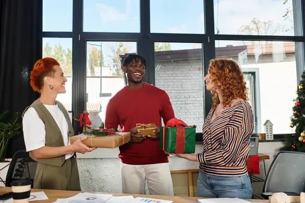 Celebrating the holiday spirit, coworkers share gifts and smiles in a lively office setting. — Stock Photo