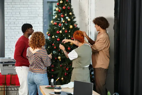 Coworkers embrace the festive spirit while decorating a Christmas tree at the office. — Stock Photo