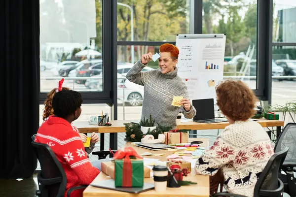 A cheerful group of young coworkers enjoys a Christmas celebration while sharing gifts and laughter. — Stock Photo