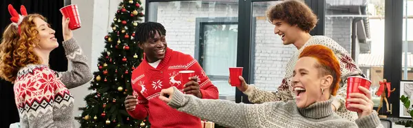 Um grupo alegre de jovens colegas de trabalho compartilha risos e bebidas durante sua celebração de Natal. — Fotografia de Stock