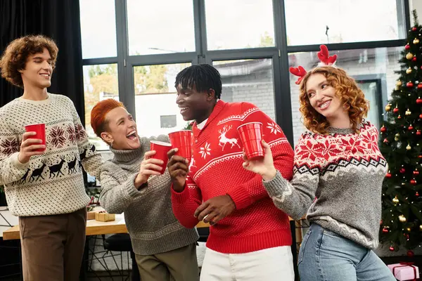 A group of young coworkers enjoys drinks while sharing laughs during a Christmas celebration. — Stock Photo