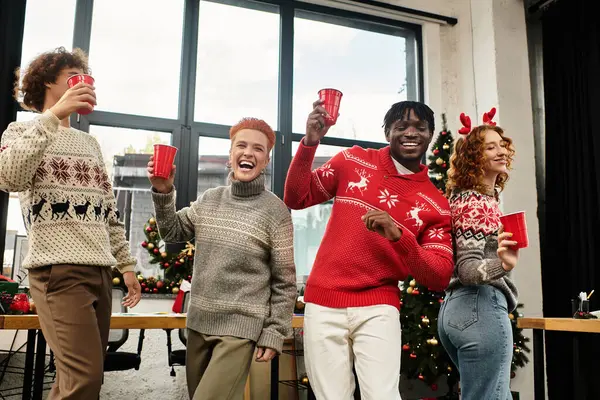 Colleagues share laughs and raise cups in celebration of Christmas at their workplace. — Stock Photo