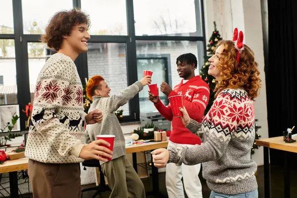 Giovani professionisti si godono una vivace festa di Natale con bevande e risate in ufficio. — Foto stock