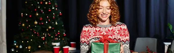 Cheerful woman with present in hands in festive sweater in office. — Photo de stock