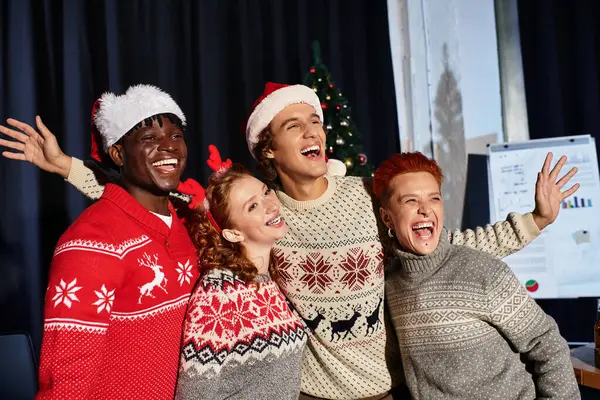 Young coworkers in holiday sweaters laugh and pose together at a Christmas celebration. — Stock Photo