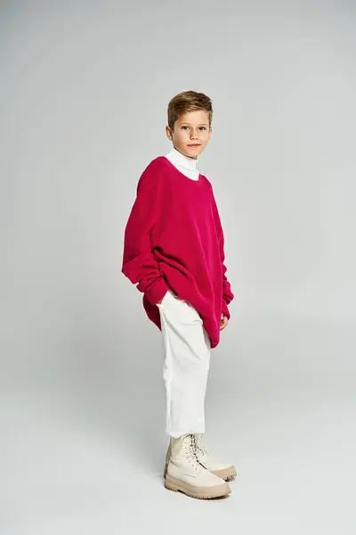 A young boy showcases a bright red sweater and white trousers, exuding a winter vibe. — Stock Photo