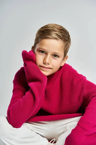 A young boy dressed in a colorful sweater sits relaxed, showcasing a cheerful expression. — Stock Photo