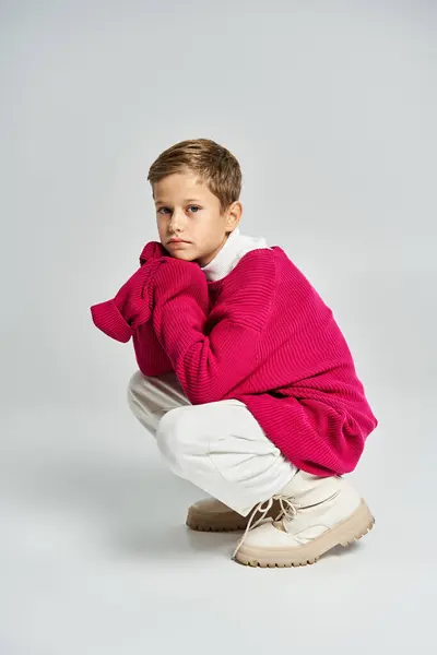 A young boy dressed in colorful winter attire sits thoughtfully, conveying a cozy vibe. — Stock Photo
