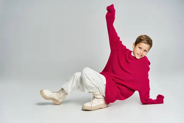 A cheerful young boy in a cozy sweater plays on the floor with a big smile, embracing winter fun. — Stock Photo