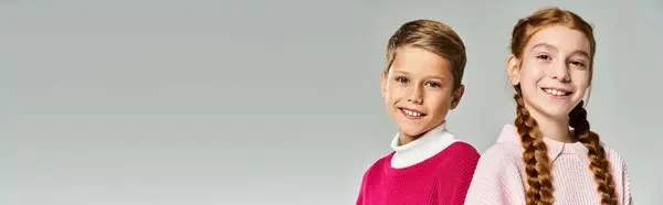 Dos niños alegres vistiendo ropa de abrigo expresan felicidad durante una estación fría. - foto de stock