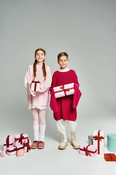 Due bambini allegri stanno orgogliosi con regali di festa, trasudando calore e spirito festivo. — Foto stock