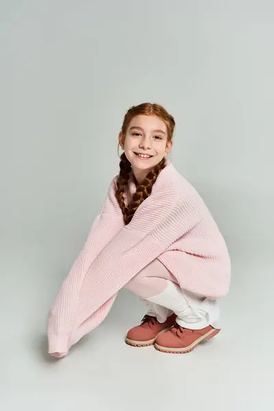 Una ragazza allegra si avvolge in un accogliente maglione rosa, irradiando gioia e calore invernale. — Foto stock
