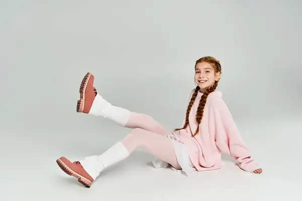 A cheerful young girl enjoys a playful moment dressed in cozy winter clothing indoors. — Stock Photo