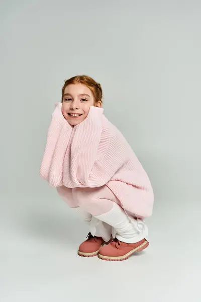 A young girl smiles widely in her cozy, oversized winter sweater, embracing the season. — Stock Photo