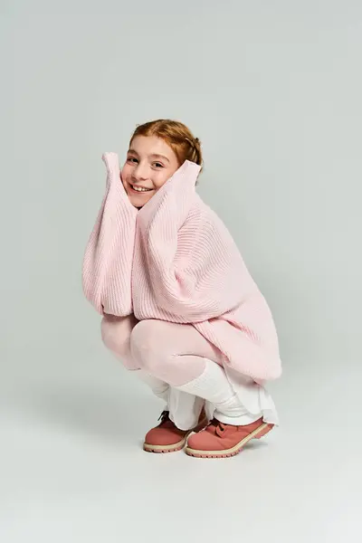 A joyful girl snuggles in oversized winter clothing, radiating warmth and cheerfulness. — Stock Photo