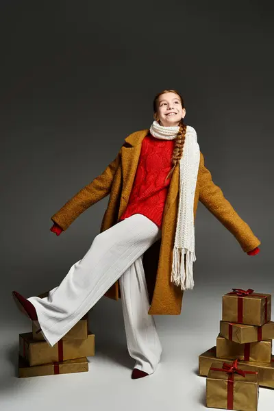 Una chica alegre en ropa de invierno posa con regalos envueltos para las fiestas. - foto de stock