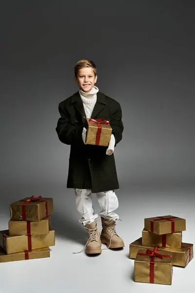 A young boy dressed warmly smiles while holding a present amidst beautifully wrapped gifts. — Stock Photo