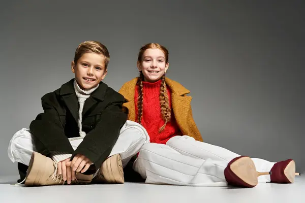 Two cheerful children display winter fashion joyfully, wearing cozy sweaters and striking poses. — Stock Photo