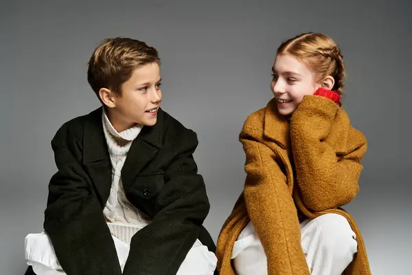 Two children dressed in warm winter layers enjoy a cheerful interaction in a cozy setting. — Stock Photo