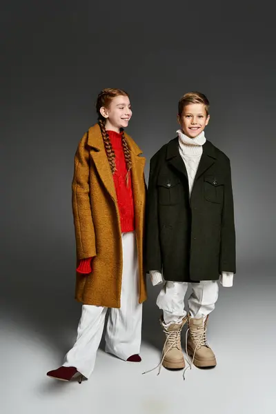Two children wearing oversized winter coats and warm boots ready for a fun snowy adventure. — Stock Photo