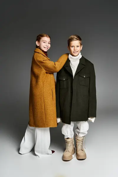 Due bambini che indossano abiti invernali oversize sorridono gioiosamente mentre posano all'interno. — Foto stock