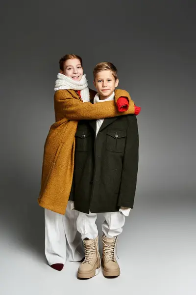 A pair of children share a warm embrace, showcasing their cozy winter outfits in a playful moment. — Stock Photo