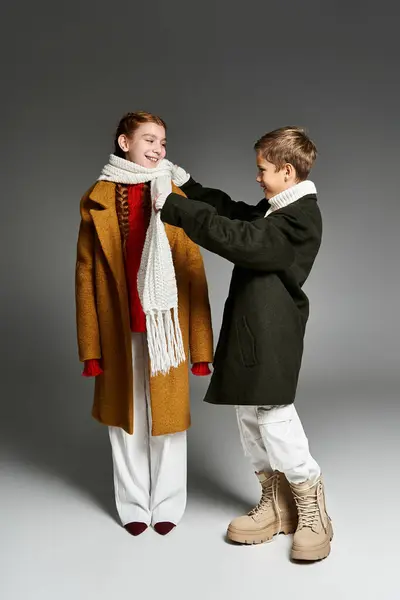 Two kids enjoy a playful moment as one wraps a scarf around the other in cozy winter wear. — Stock Photo