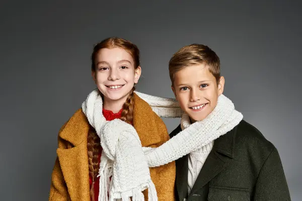 Two joyful kids in vibrant winter outfits are playfully wrapped in a scarf, exuding warmth. — Stock Photo