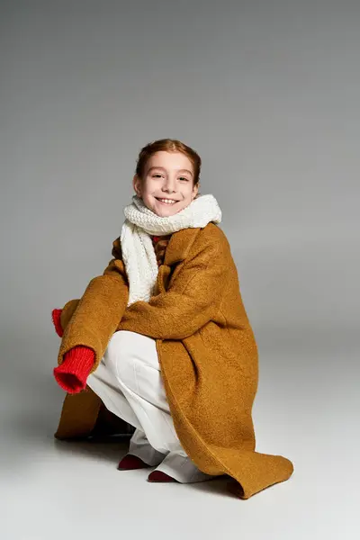 A young girl dressed in warm, inviting layers plays warmly against a neutral backdrop. — Stock Photo