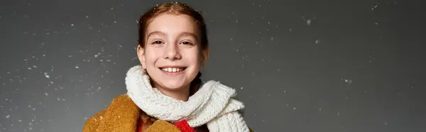 A cheerful girl wearing a warm scarf and coat enjoys a delightful winter moment while smiling. — Photo de stock