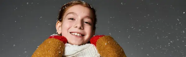 A young girl beams in cozy layers as she celebrates winter amid the snowfall. — Stock Photo