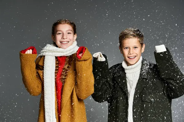 Children enjoy a snowy day, dressed warmly and laughing while surrounded by falling snowflakes. — Stock Photo