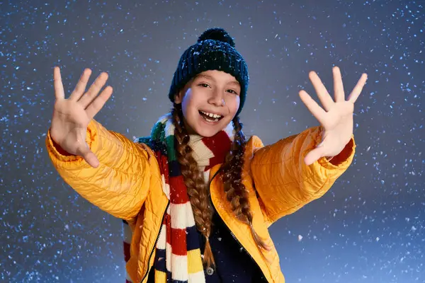 A cheerful girl wearing a colorful scarf and beanie joyfully plays in the snow. — Stock Photo