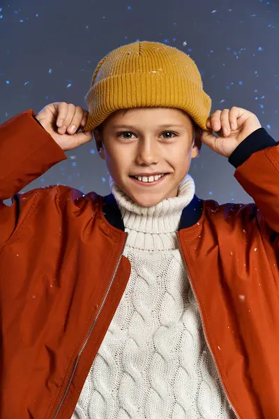 The boy beams with joy as he wears a knitted sweater and colorful beanie in a snowy setting. — Foto stock