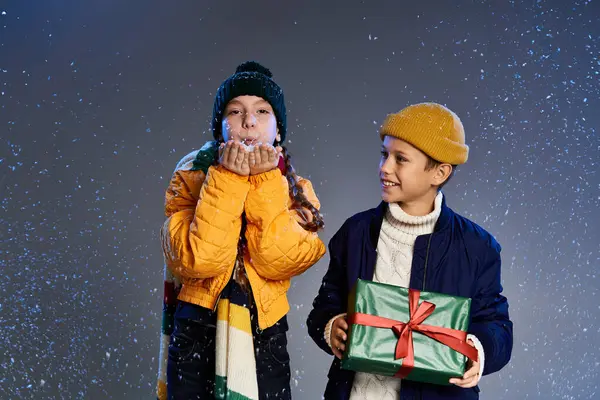 Two children dressed warmly with gifts basking in the joy of winter festivities — Stock Photo
